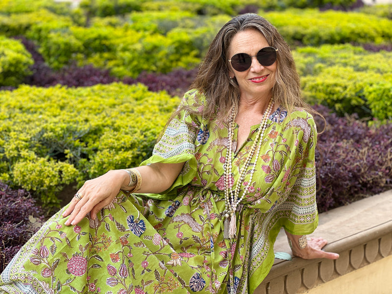 Model wearing lime green block printed floral maxi kaftan dress by pax philomena with intricate border and a silver mala and rose quartz mala