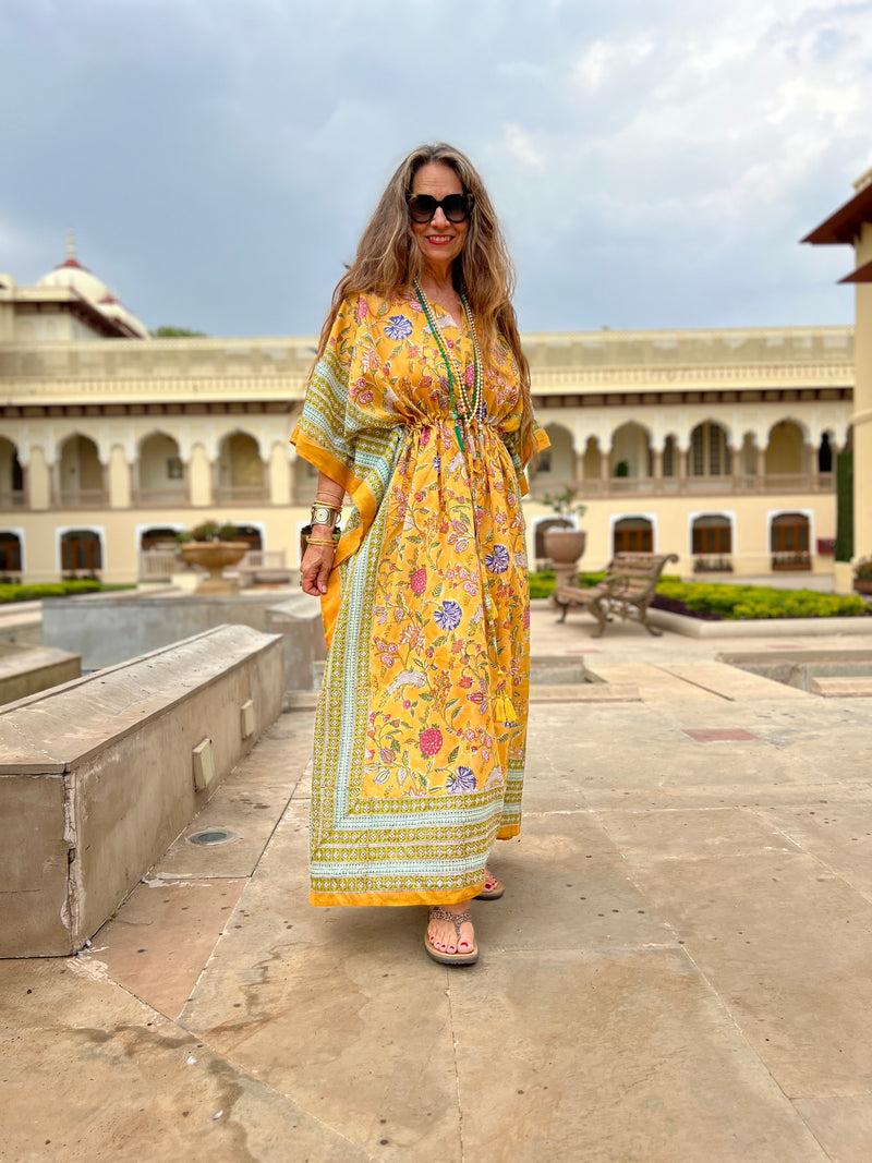 model wearing golden yellow block printed floral maxi kaftan dress by pax philomena with intricate border and adjustable drawstring waist with intricate tassels